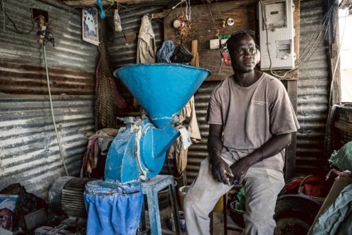 Sukuta的磨坊经营者Amadou Gaye站在磨粉机旁，断电使机器无法运转。 / MUHAMADOU BITTAYE／AFP ...